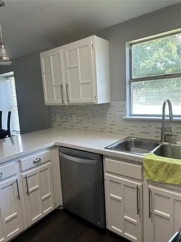 a kitchen with white cabinets and sink