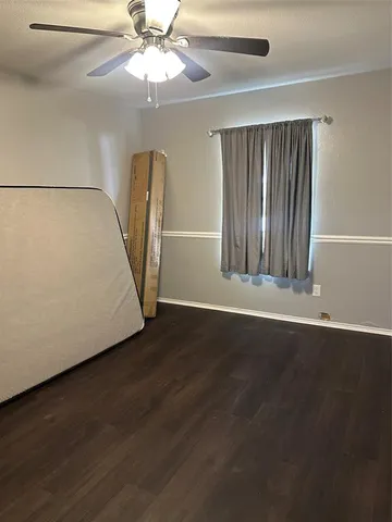 an empty room with wooden floor chandelier fan and windows