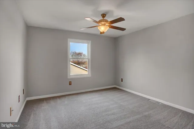 an empty room with a window and a fan