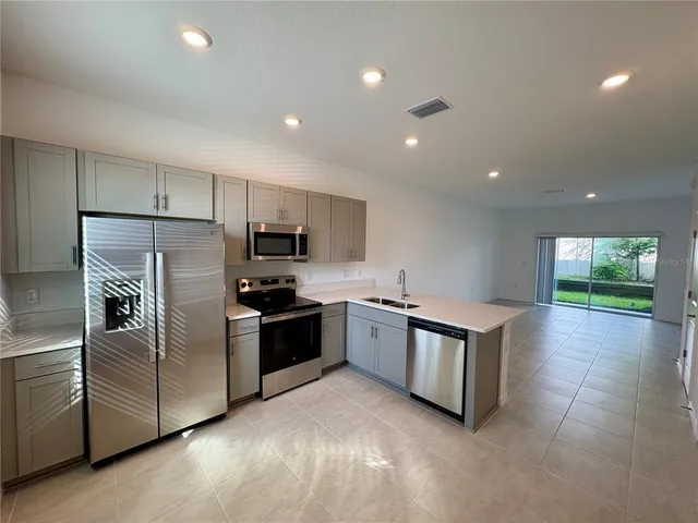 a large kitchen with stainless steel appliances granite countertop a large counter top a stove a chimney a sink and a refrigerator