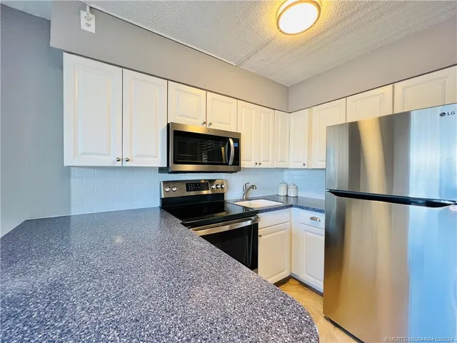 a kitchen with a refrigerator a stove top oven a sink and cabinets