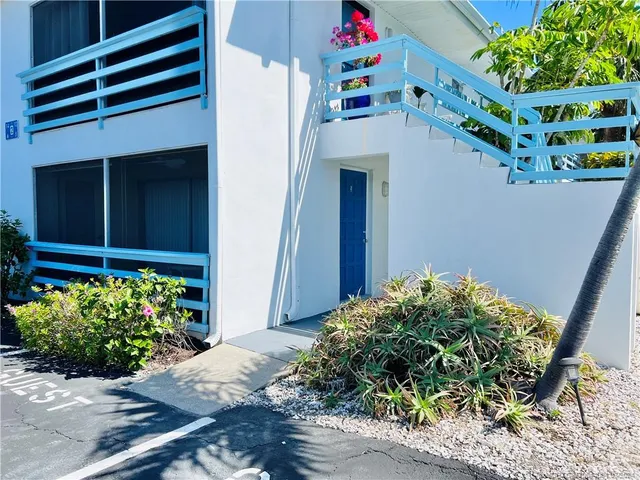 a white house with a flower garden and a yard