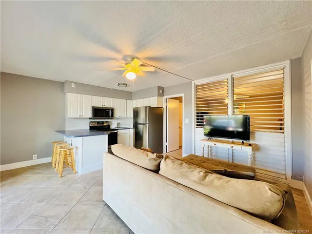 a living room with stainless steel appliances furniture a flat screen tv and a window