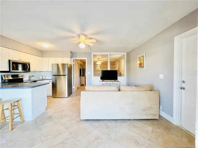 a living room with stainless steel appliances furniture and a view of kitchen