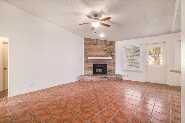 a view of an empty room with window and a fireplace