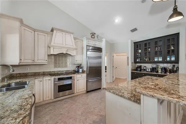 a kitchen with granite countertop a stove sink and refrigerator