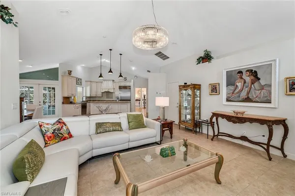 a living room with furniture chandelier and kitchen view
