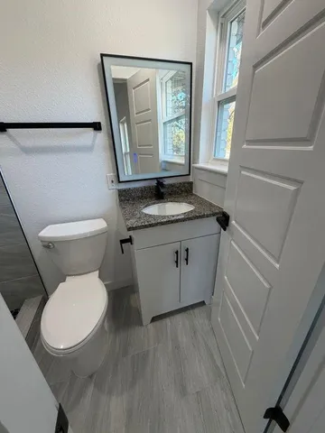 a bathroom with a granite countertop toilet a sink and a mirror