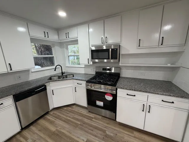 a kitchen with granite countertop white cabinets and appliances