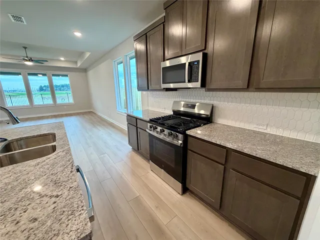 a kitchen with granite countertop stainless steel appliances a stove sink and microwave