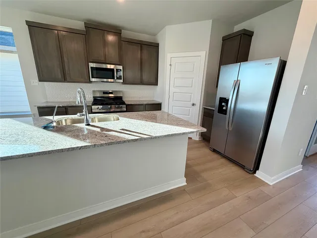 a kitchen with granite countertop a refrigerator microwave and sink