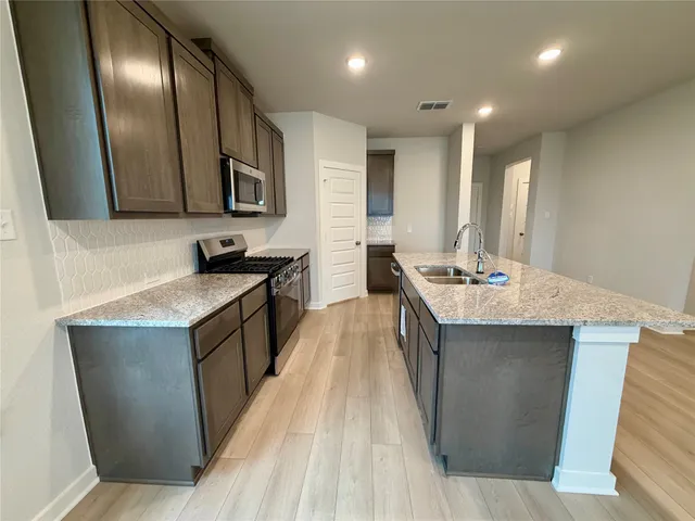 a kitchen with stainless steel appliances granite countertop a sink stove and refrigerator