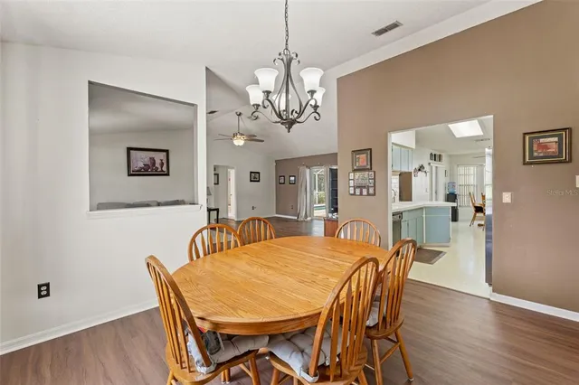 a dining room with wooden floor a chandelier a wooden table and chairs