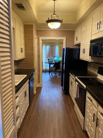 a kitchen with granite countertop wooden floors a stove and a microwave