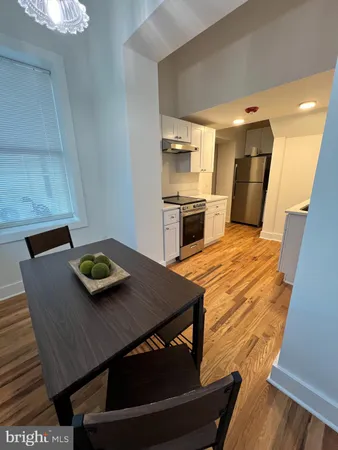 a living room with stainless steel appliances furniture a rug and a kitchen view