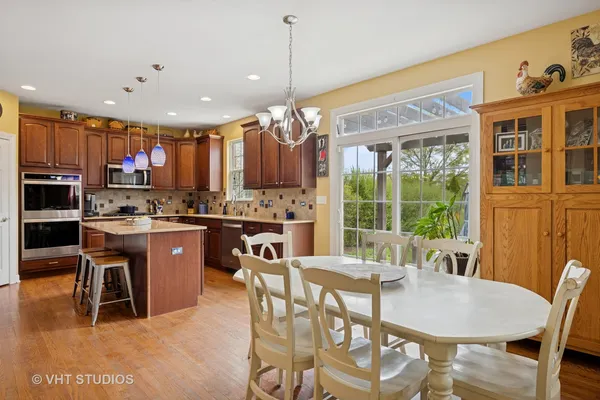 a kitchen with kitchen island granite countertop wooden floors and a view of living room