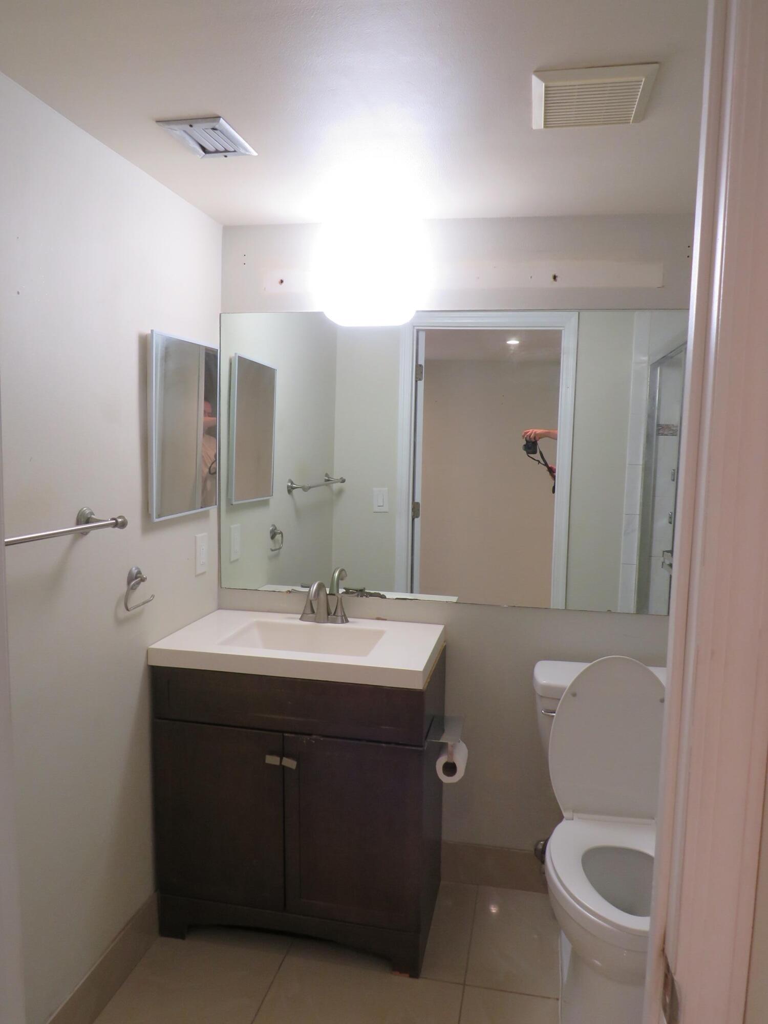 335 Pine Ridge Circle, Unit D1 Greenacres, FL 33463 - Photo 22 of 30 a bathroom with a toilet a sink and mirror
