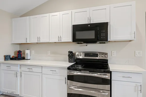 a kitchen with stainless steel appliances granite countertop grey cabinets a stove a sink and dishwasher