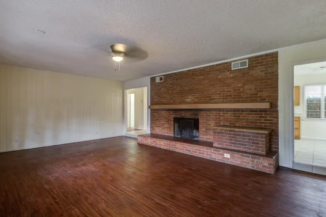 an empty room with wooden floor and fireplace