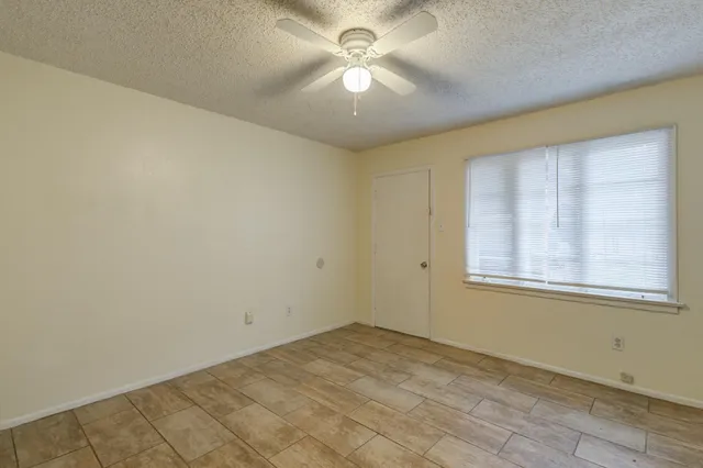 a view of empty room with window and ceiling fan