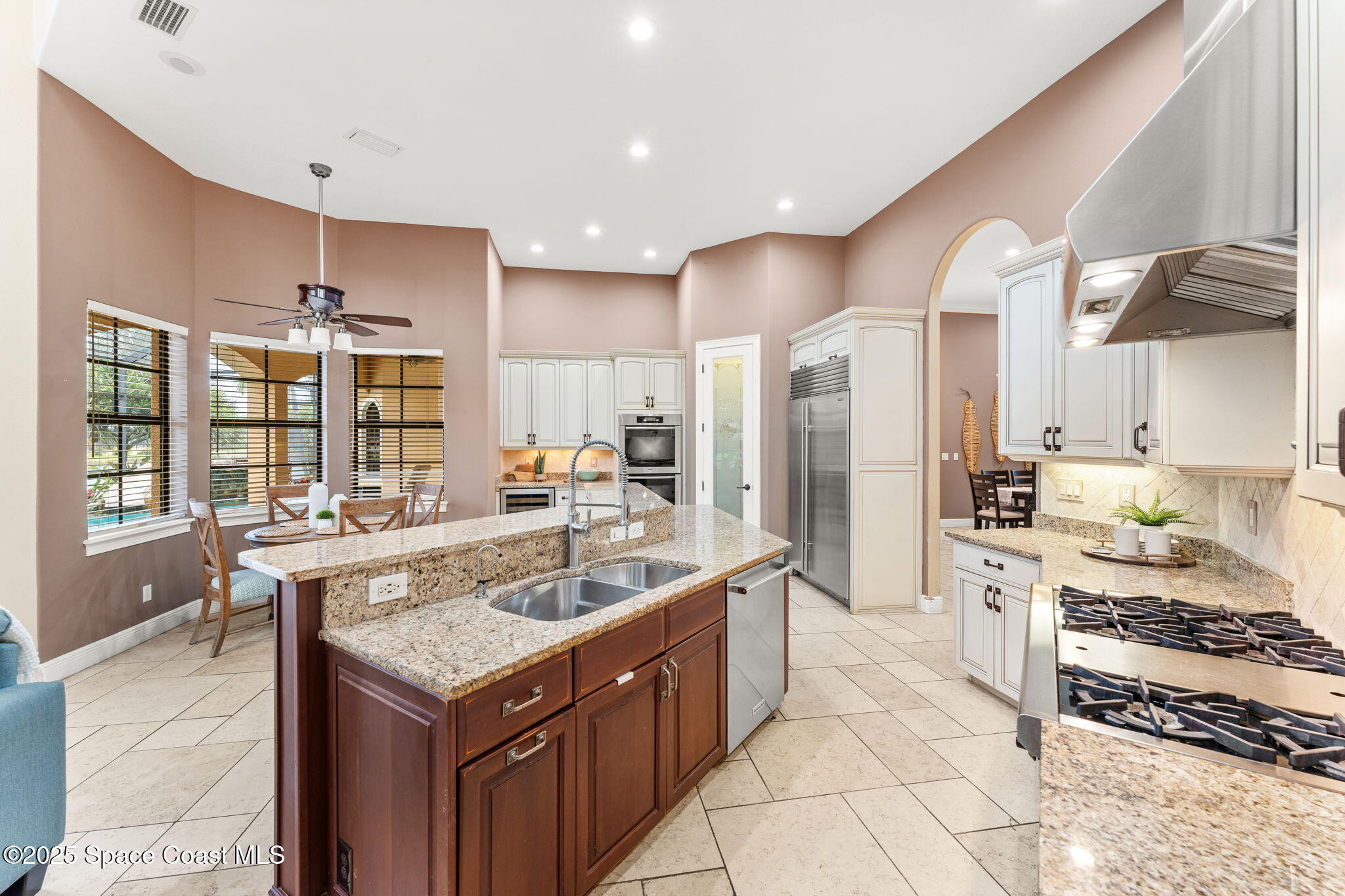 6205 Anello Drive Melbourne, FL 32940 - Photo 13 of 49 a large kitchen with kitchen island a large counter top space a sink stainless steel appliances and cabinets