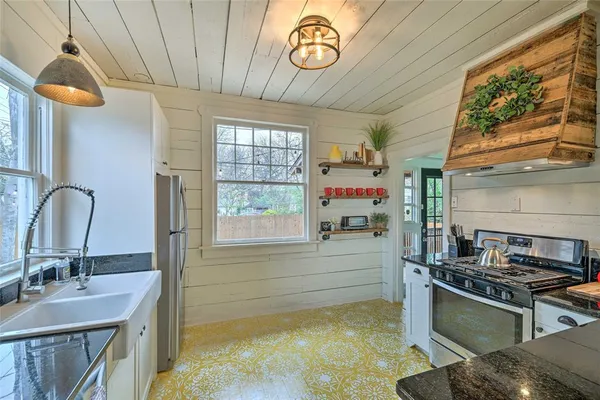 a kitchen with kitchen island a stove a sink and a large window