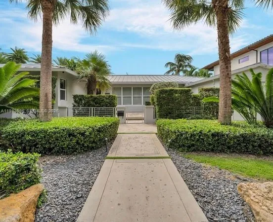 a front view of a house with a garden and palm trees