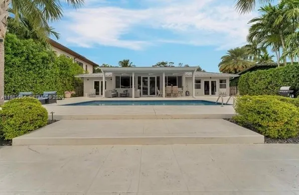 front view of house with a yard and palm trees