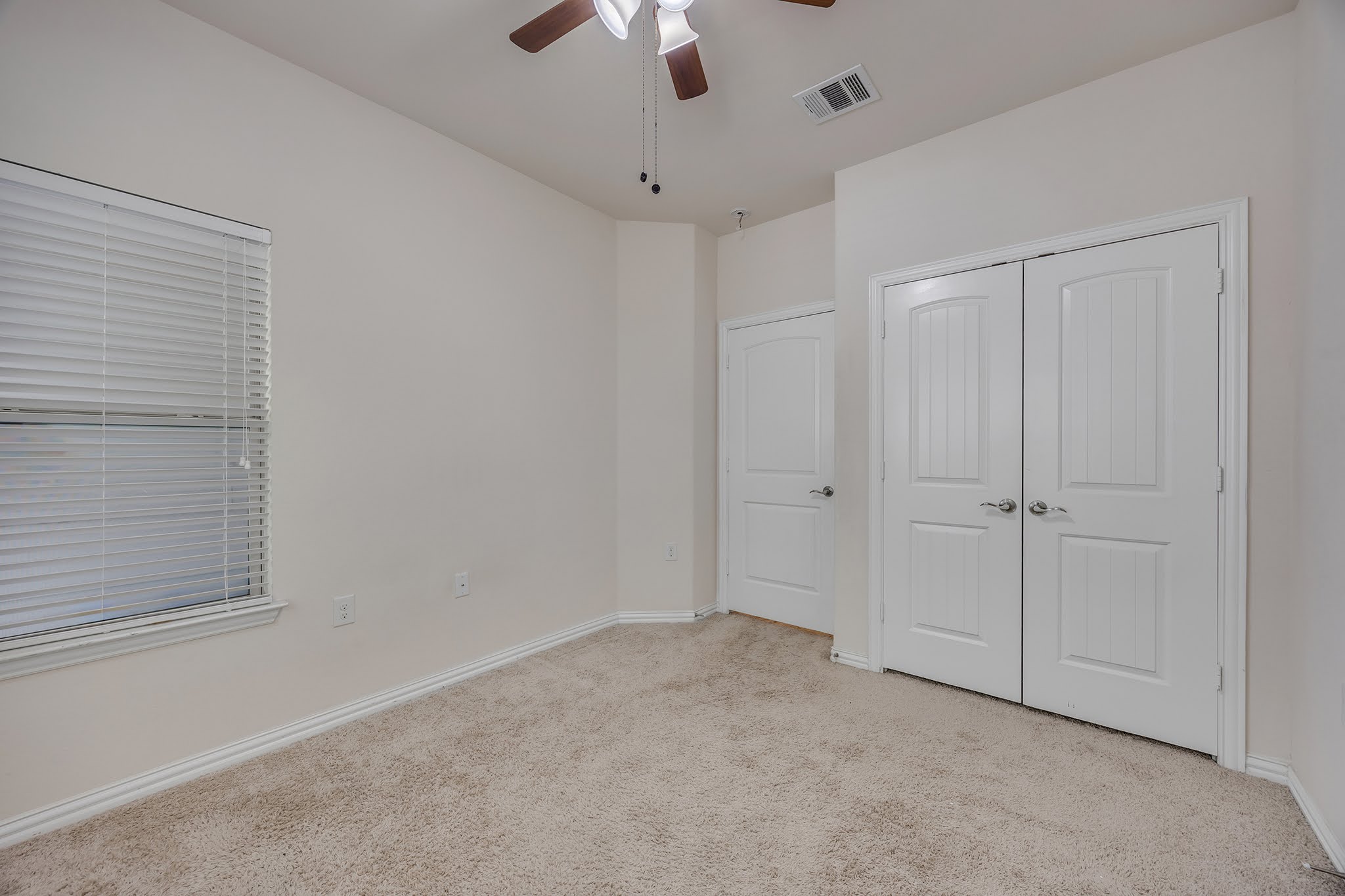7212 Vail Ridge Street Austin, TX 78744 - Photo 10 of 26 Comfortable carpeted bedroom features a window with blinds and convenient ceiling fan.