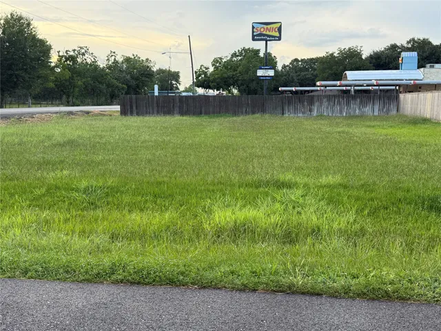a view of a lake with a yard and trees in the background