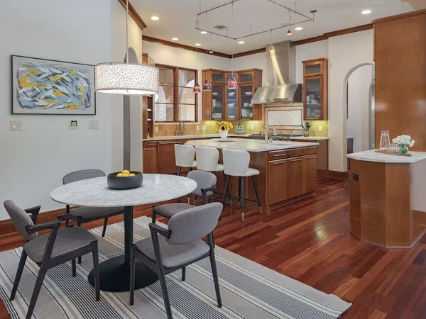 a kitchen with stainless steel appliances kitchen island granite countertop a table chairs and a refrigerator