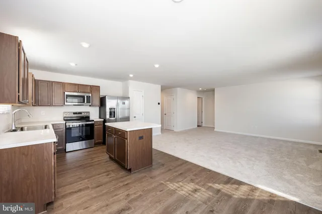 a kitchen with stainless steel appliances granite countertop a stove top oven a sink a refrigerator white cabinets and wooden floor