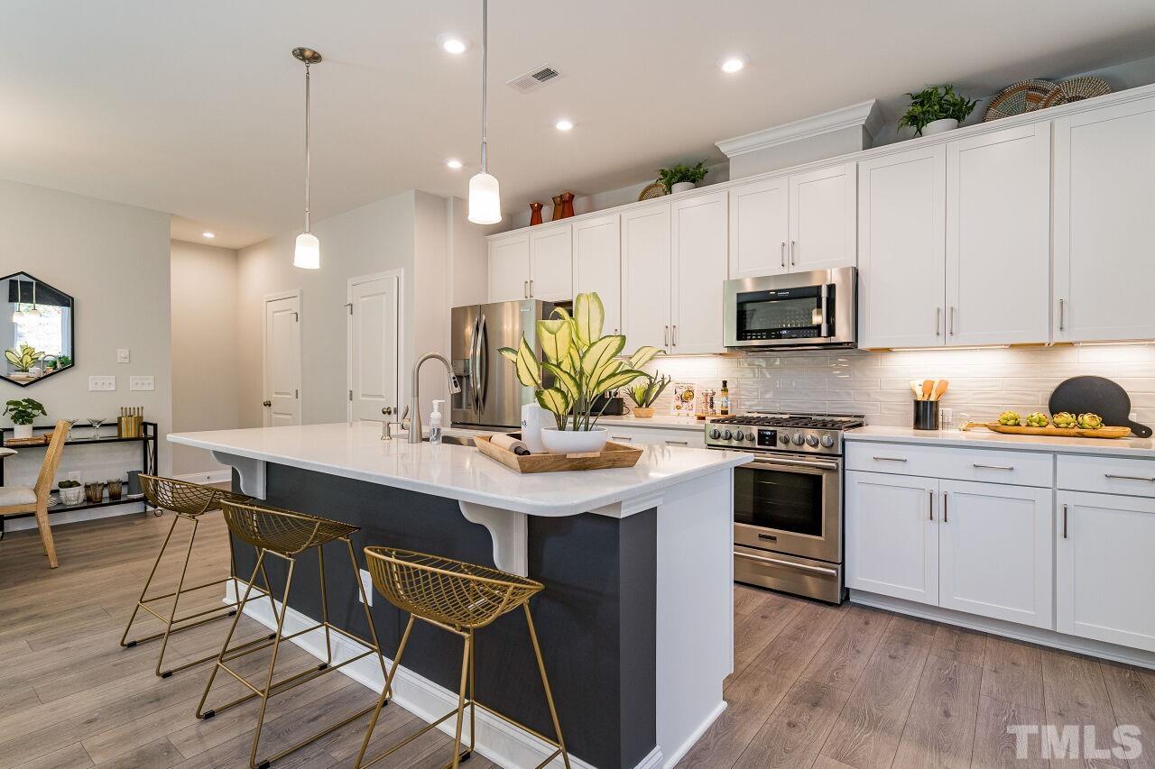 3107 Dunnock Drive, Unit 6 Durham, NC 27713 - Photo 12 of 27 a kitchen with kitchen island granite countertop a sink counter top space appliances and cabinets