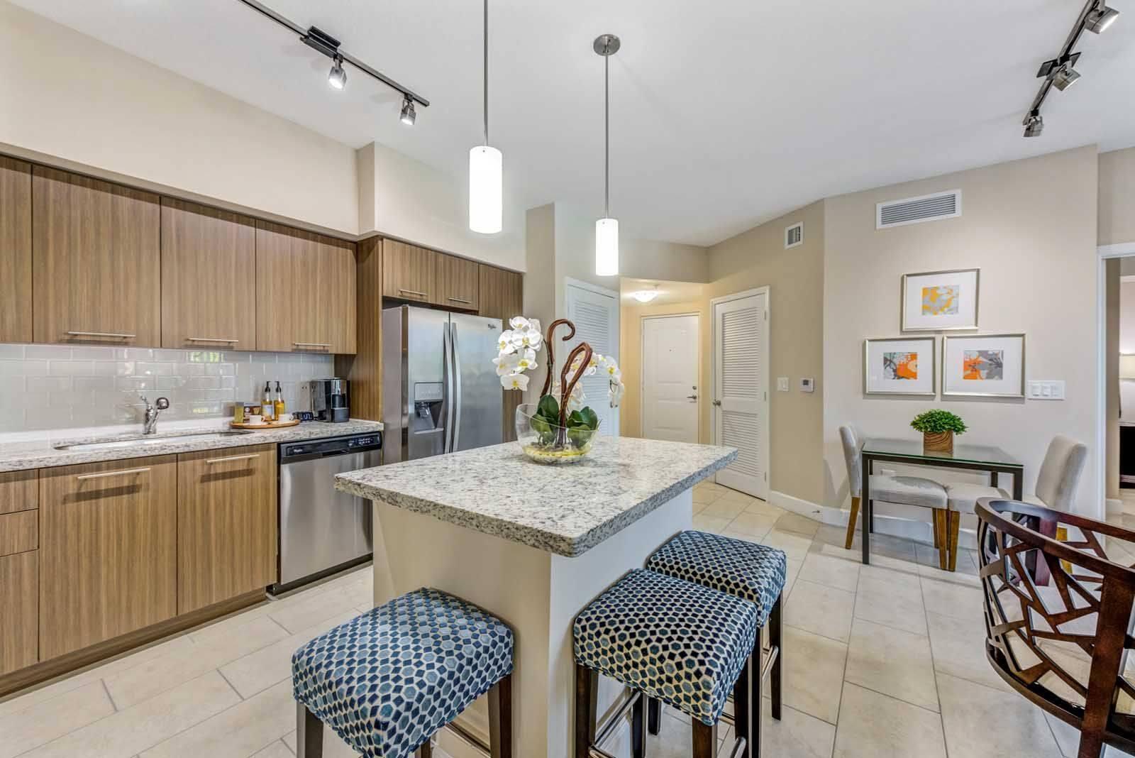 16812 Southwest 137th Avenue, Unit 833 Miami, FL 33177 - Photo 6 of 14 a kitchen with stainless steel appliances granite countertop a sink a stove a kitchen island with chairs and white cabinets