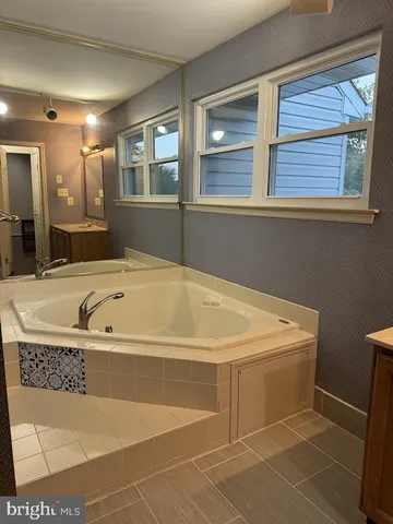 a bathroom with a tub a sink and mirror