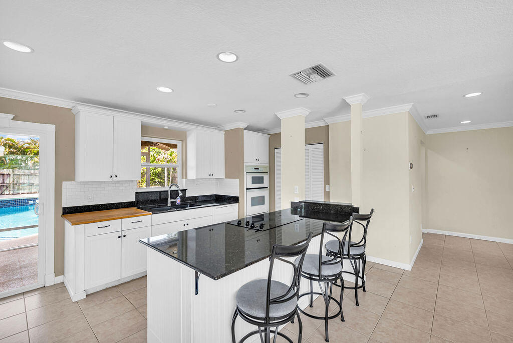 614 Southeast Flamingo Avenue Stuart, FL 34996 - Photo 11 of 49 a kitchen with granite countertop sink table and chairs