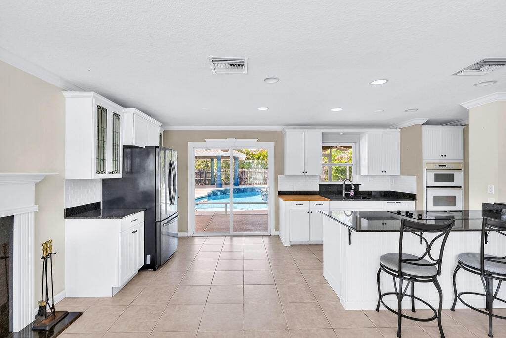 614 Southeast Flamingo Avenue Stuart, FL 34996 - Photo 22 of 49 a kitchen with stainless steel appliances a refrigerator a stove a sink a dining table and chairs