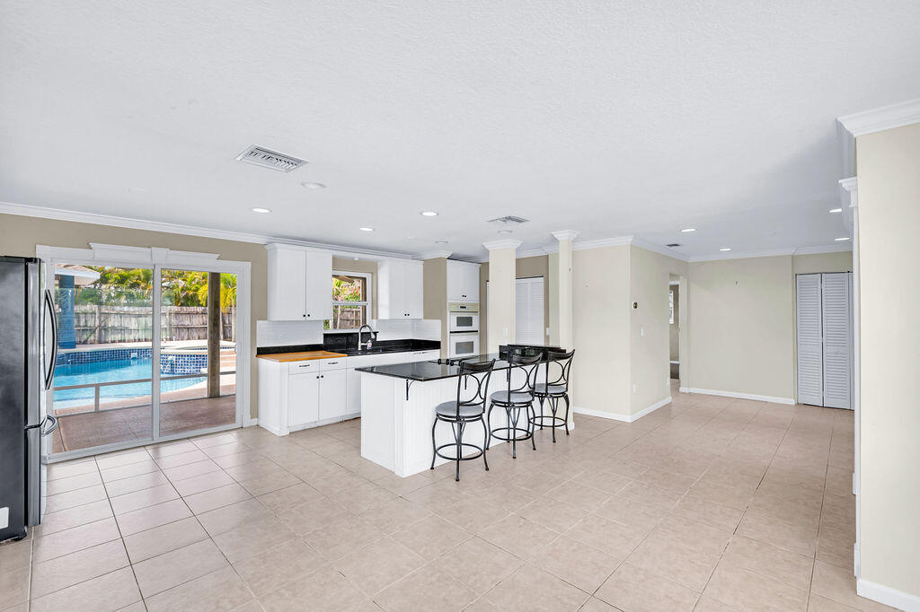 614 Southeast Flamingo Avenue Stuart, FL 34996 - Photo 9 of 49 a kitchen with a dining table chairs and large window