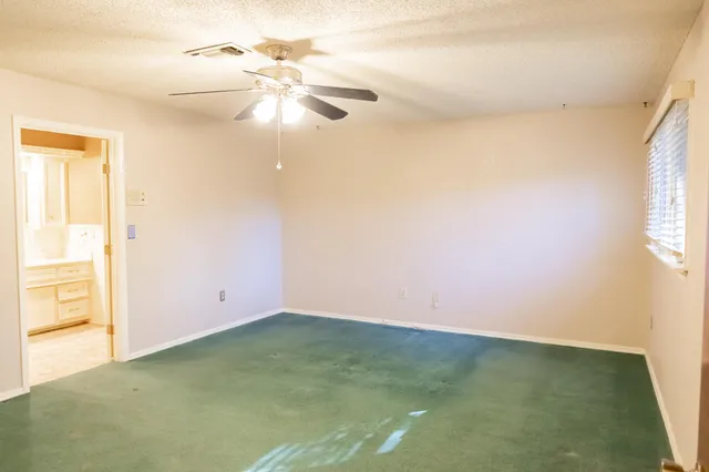en empty room with windows and chandelier fan