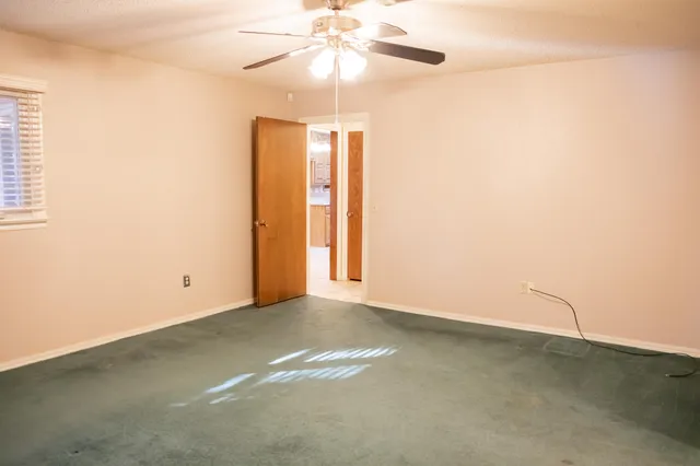 an empty room with a fan and a window