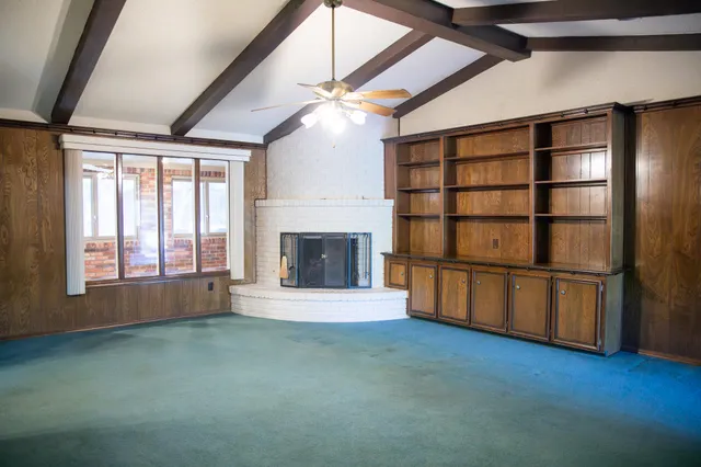 a view of an empty room with a window and fireplace