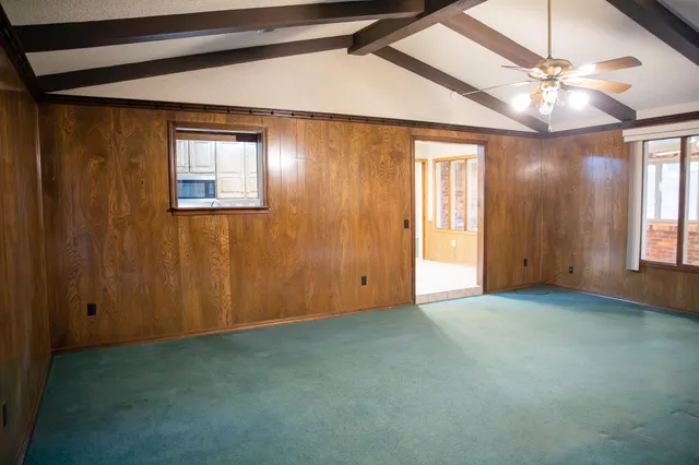 en empty room with windows and chandelier fan