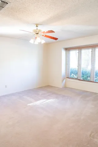 an empty room with windows and chandelier fan