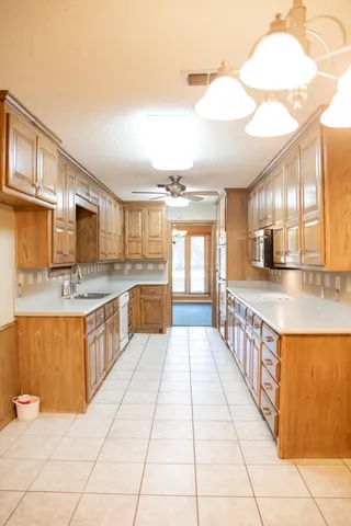 a large white kitchen with granite countertop a sink and dishwasher a stove with wooden cabinets