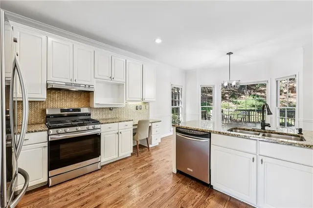 a kitchen with granite countertop white cabinets and stainless steel appliances