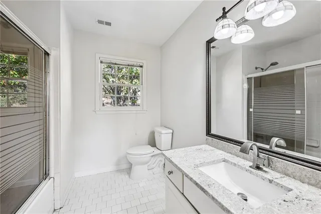 a bathroom with a granite countertop sink a toilet and a mirror