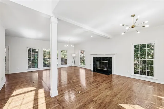 a view of an empty room with wooden floor fireplace and a window