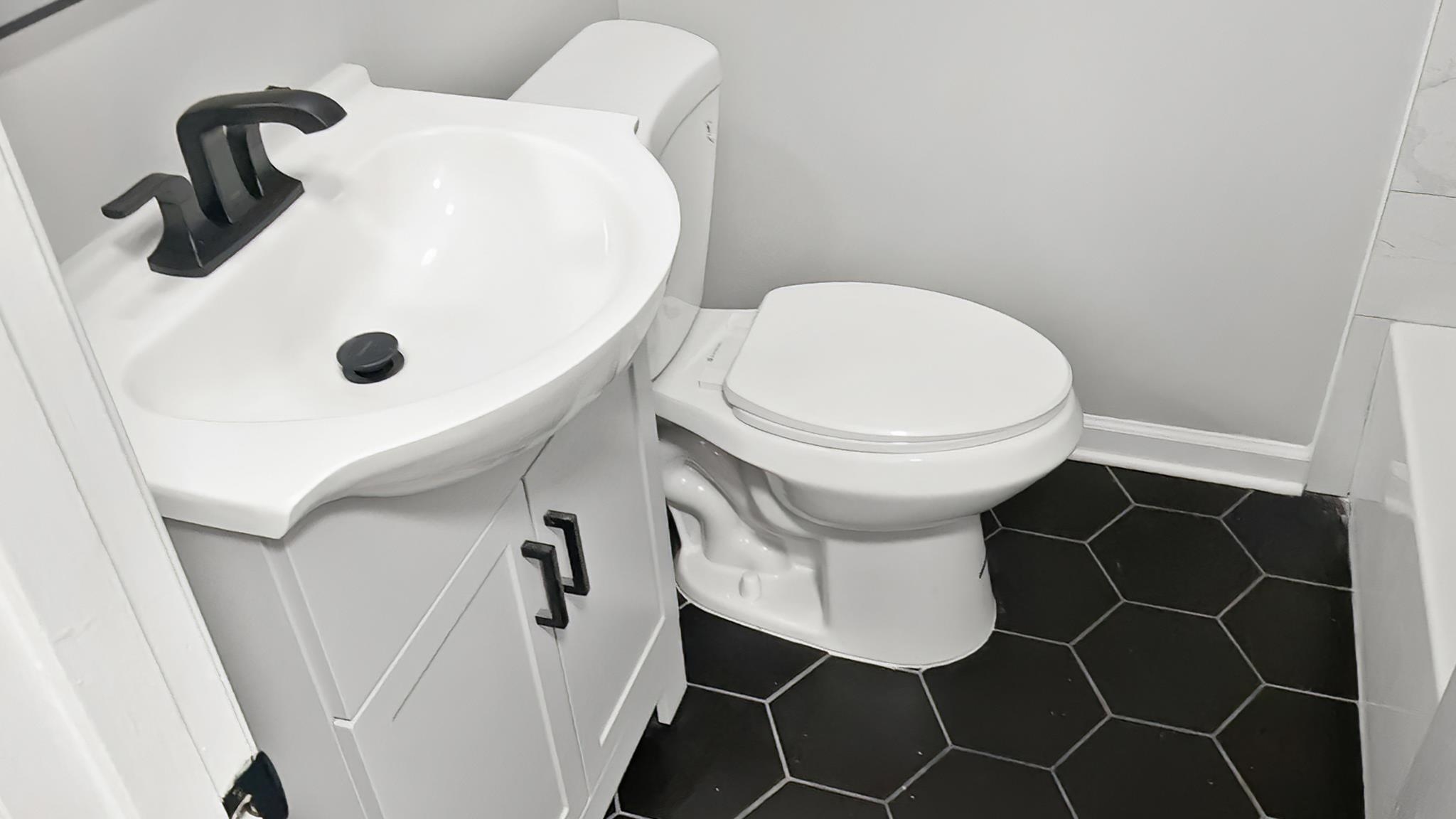 335 Homeville Road Collierville, TN 38017 - Photo 7 of 11 Bathroom featuring a white corner vanity with a black faucet, a white toilet, and black hexagonal floor tiles