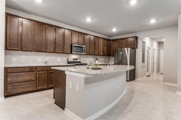 a kitchen with kitchen island granite countertop a stove refrigerator and cabinets