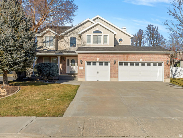 969 Addington Circle Sandy, UT 84094 - Photo 1 of 1 Traditional-style house featuring a front yard, concrete driveway, covered porch, and brick siding